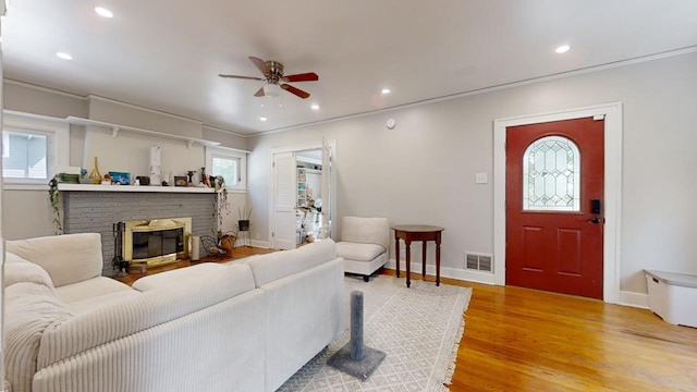 living room featuring wood-type flooring, plenty of natural light, ceiling fan, and a fireplace