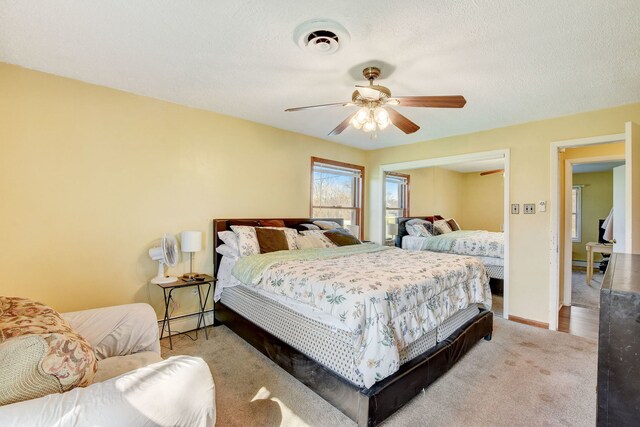 bedroom featuring ceiling fan, a textured ceiling, and light carpet