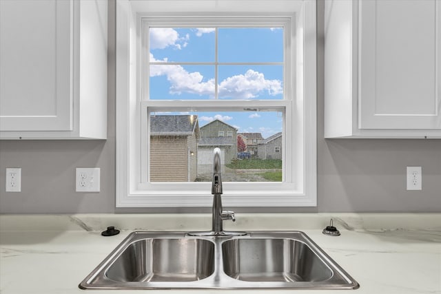 room details with light stone counters, white cabinetry, and sink