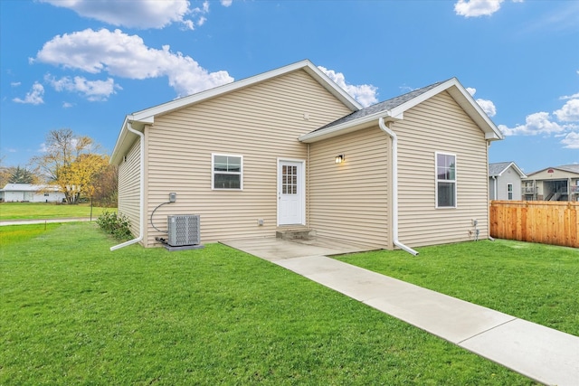 rear view of property with a patio, cooling unit, and a lawn