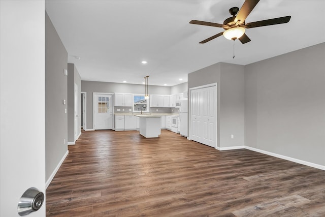 unfurnished living room with ceiling fan, sink, and dark hardwood / wood-style floors