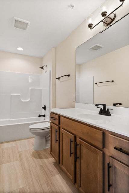 full bathroom featuring hardwood / wood-style flooring, vanity, bathing tub / shower combination, and toilet