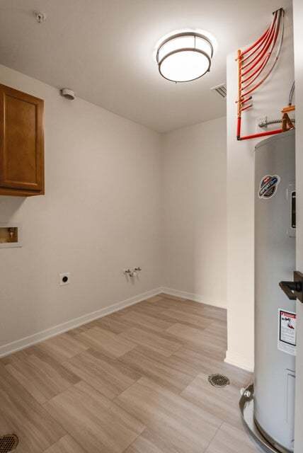 washroom with cabinets, water heater, and light hardwood / wood-style flooring