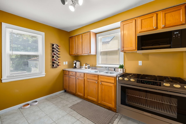 kitchen featuring sink, light tile patterned floors, and stainless steel range