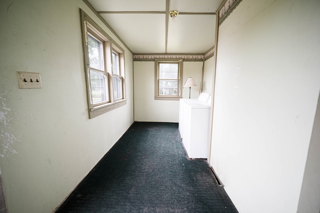 hall with washer / dryer and dark colored carpet