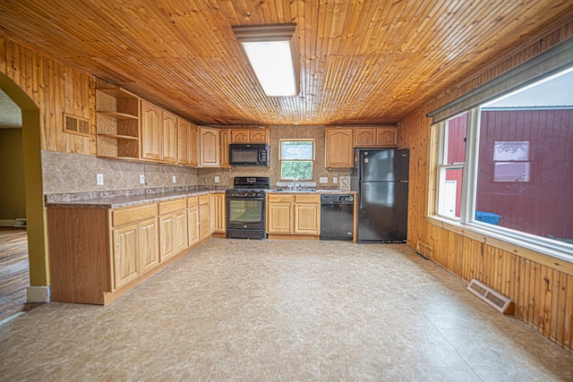 kitchen featuring sink, black appliances, decorative backsplash, and wood walls