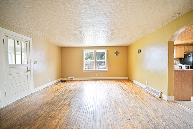 unfurnished living room with a textured ceiling and light wood-type flooring