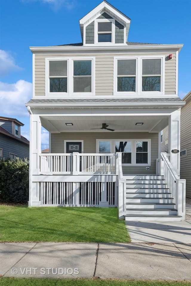 view of front of property with ceiling fan, covered porch, and a front lawn