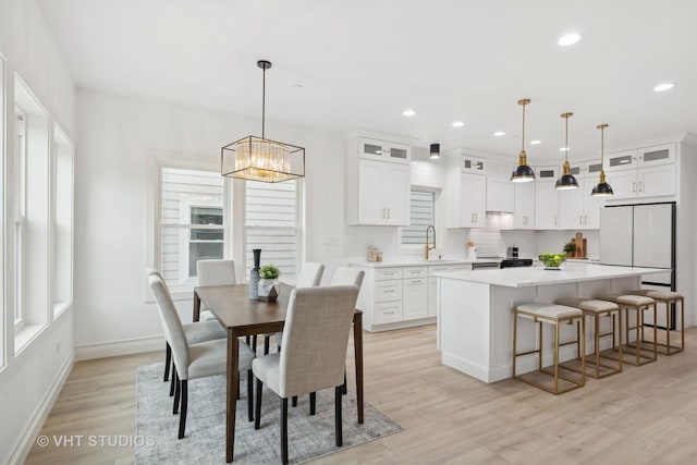 dining space with sink, a notable chandelier, and light wood-type flooring