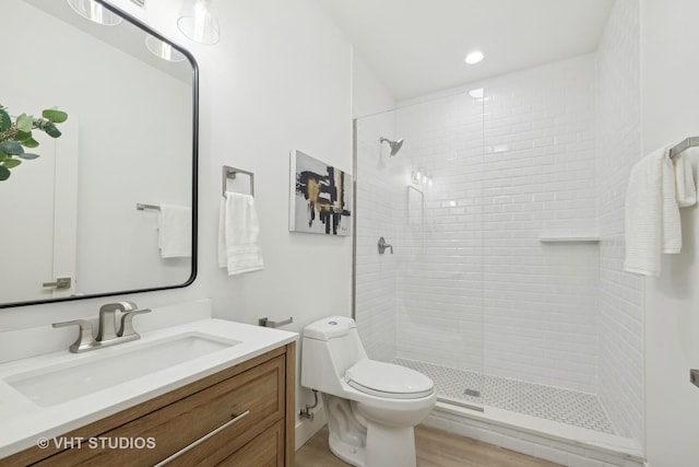 bathroom featuring vanity, toilet, and a tile shower