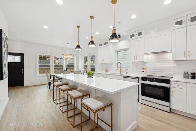 kitchen with white cabinets, a kitchen island, and range with electric stovetop