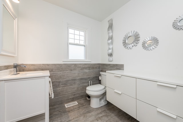 bathroom with hardwood / wood-style flooring, vanity, toilet, and tile walls