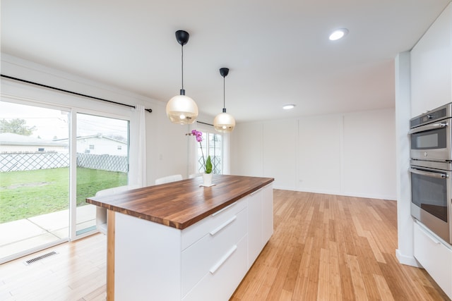 kitchen featuring white cabinets, wooden counters, and light wood-type flooring