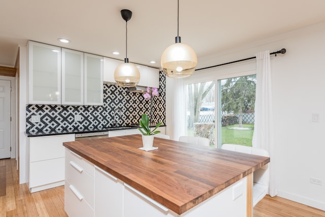 kitchen featuring backsplash, light hardwood / wood-style flooring, decorative light fixtures, and white cabinetry