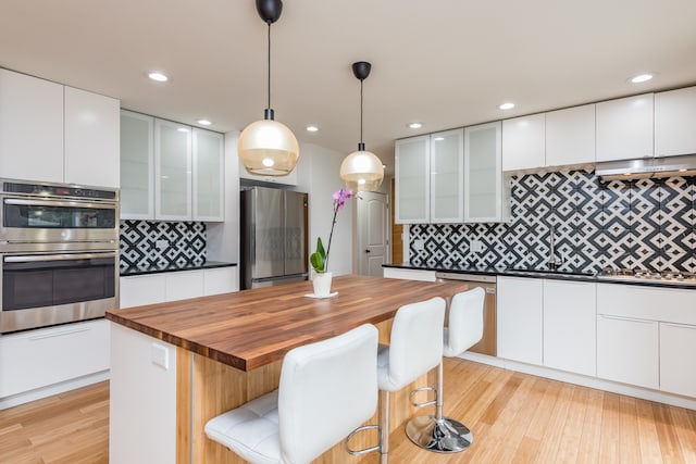 kitchen with a kitchen bar, a kitchen island, white cabinets, and stainless steel appliances