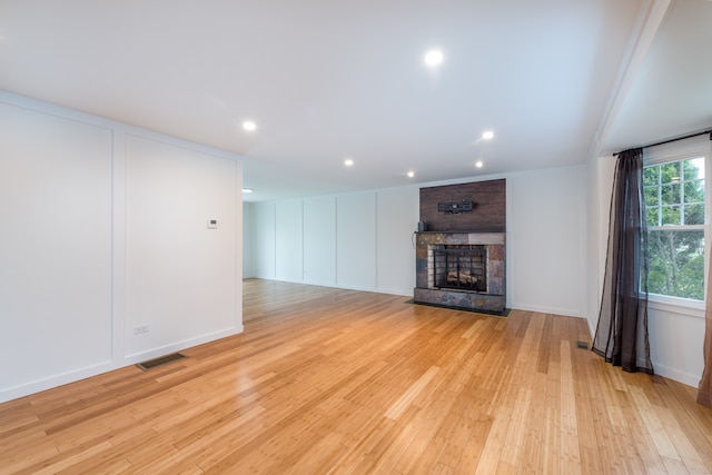 unfurnished living room featuring brick wall, a brick fireplace, and light wood-type flooring