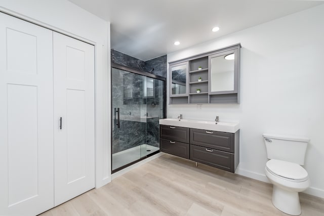 bathroom with a shower with shower door, hardwood / wood-style flooring, vanity, and toilet