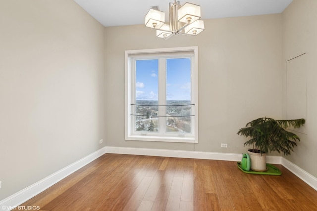 spare room featuring an inviting chandelier and wood-type flooring