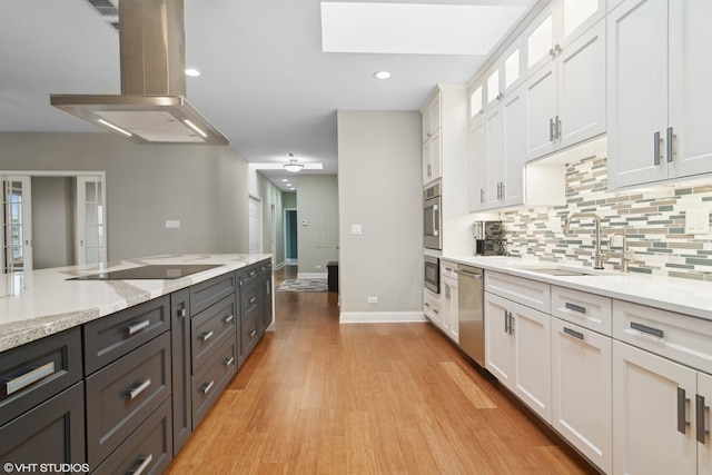 kitchen with white cabinetry, sink, island exhaust hood, light hardwood / wood-style floors, and black electric cooktop