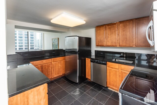 kitchen with appliances with stainless steel finishes, dark tile flooring, and sink