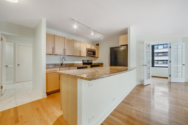 kitchen with stainless steel appliances, light stone counters, rail lighting, light brown cabinetry, and light wood-type flooring