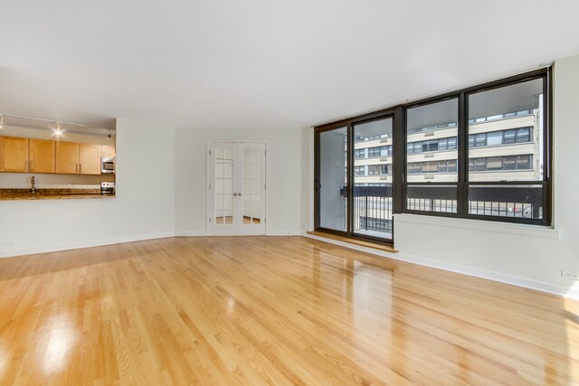 unfurnished living room with light hardwood / wood-style floors and french doors