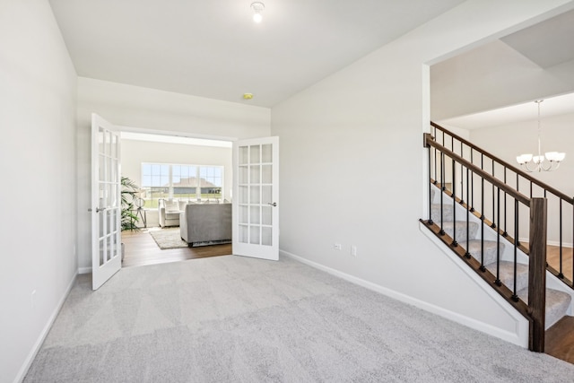 empty room featuring wood-type flooring, a chandelier, and french doors