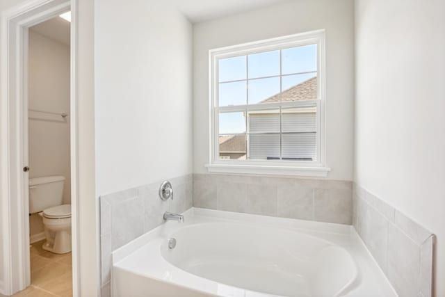 bathroom with toilet, plenty of natural light, a bathing tub, and tile patterned flooring