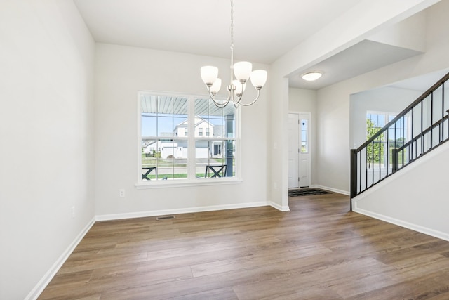 unfurnished dining area featuring hardwood / wood-style floors and a notable chandelier