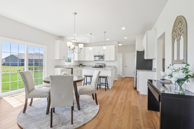 dining space with plenty of natural light, light hardwood / wood-style flooring, and a notable chandelier