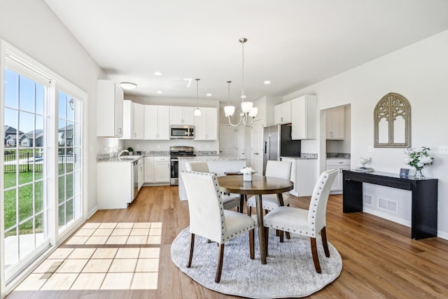 dining area with a wealth of natural light, light hardwood / wood-style flooring, a chandelier, and sink