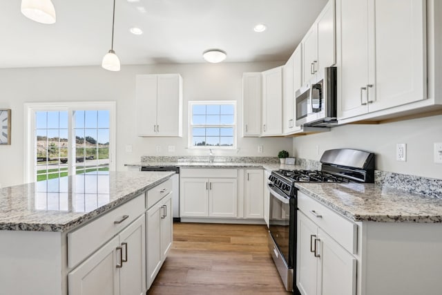 kitchen featuring light wood-type flooring, white cabinets, appliances with stainless steel finishes, and a kitchen island