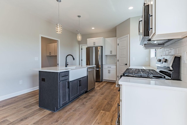 kitchen with stainless steel appliances, a kitchen island with sink, wood-type flooring, decorative light fixtures, and white cabinets