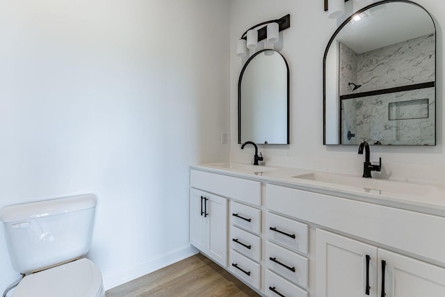 bathroom with hardwood / wood-style floors, vanity, toilet, and a shower