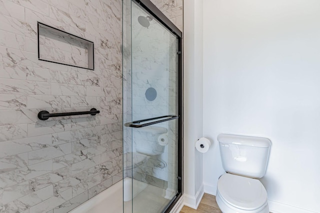 bathroom with hardwood / wood-style floors, toilet, and an enclosed shower