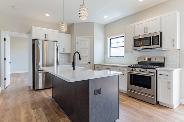 kitchen featuring appliances with stainless steel finishes, light wood-type flooring, a kitchen island with sink, and sink