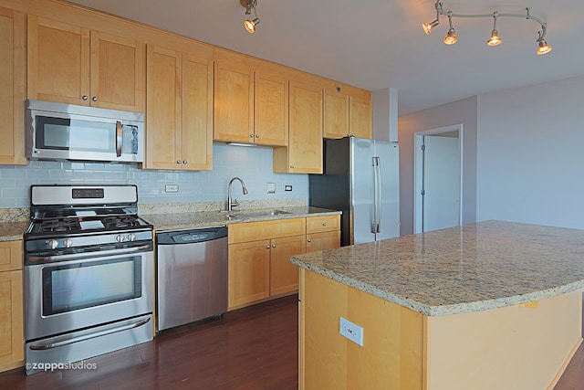 kitchen with appliances with stainless steel finishes, backsplash, dark hardwood / wood-style floors, sink, and a center island