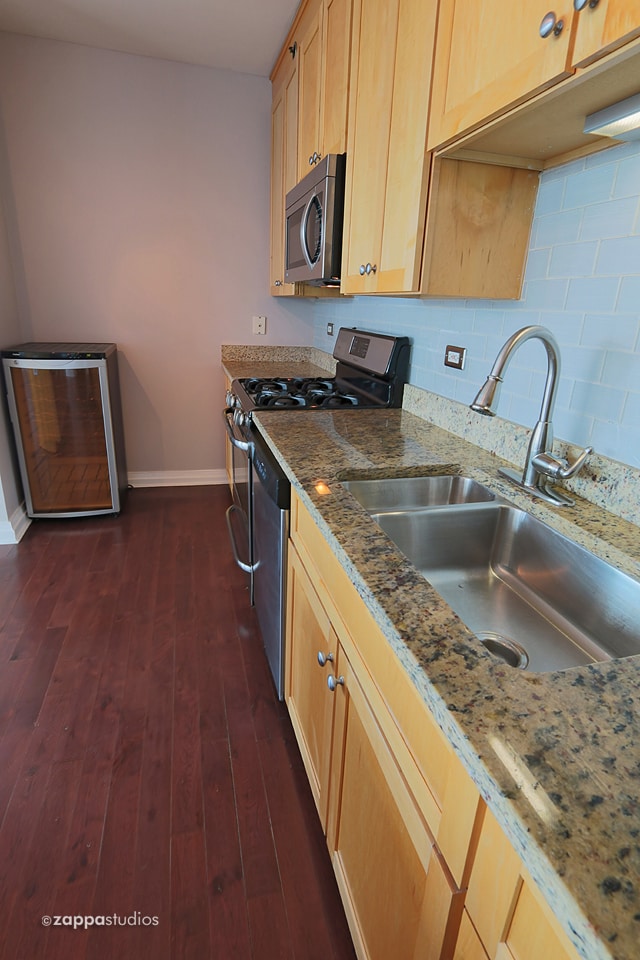 kitchen featuring dark hardwood / wood-style floors, light brown cabinetry, appliances with stainless steel finishes, sink, and tasteful backsplash