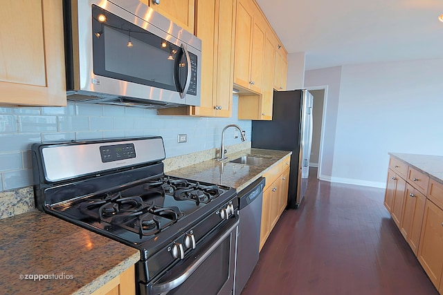 kitchen with dark hardwood / wood-style flooring, stainless steel appliances, sink, tasteful backsplash, and dark stone counters