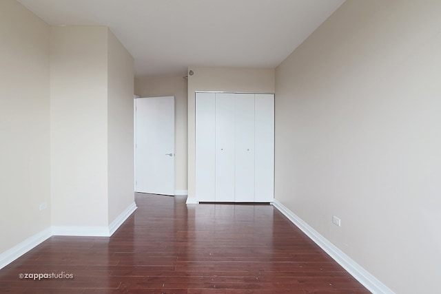 unfurnished bedroom with dark hardwood / wood-style flooring and a closet