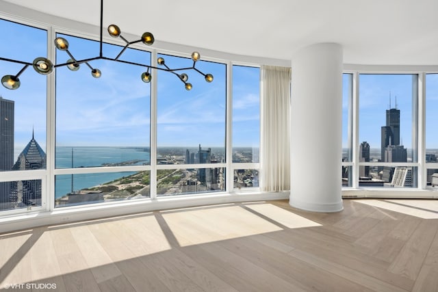 spare room with a water view, plenty of natural light, decorative columns, and expansive windows