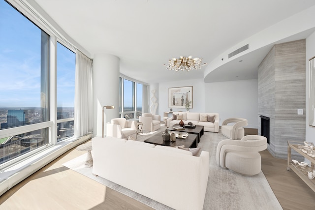 living room featuring light hardwood / wood-style floors, a fireplace, expansive windows, and an inviting chandelier