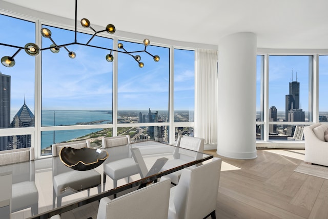 dining room with a healthy amount of sunlight, parquet flooring, a water view, and ornate columns