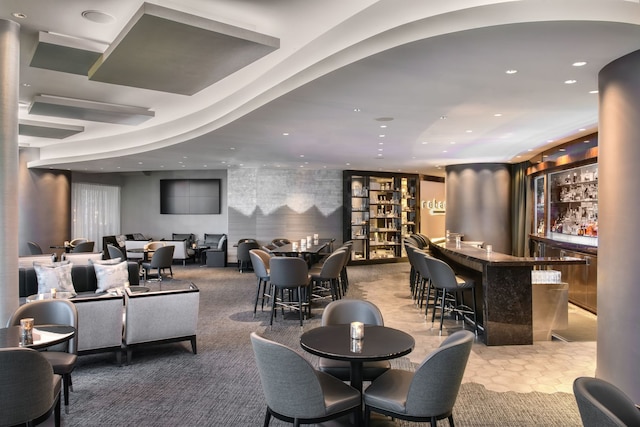 carpeted dining room featuring bar