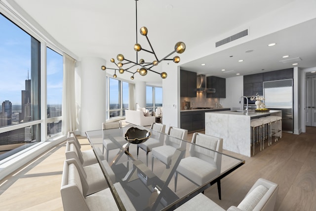 dining space featuring a notable chandelier, sink, and light hardwood / wood-style floors