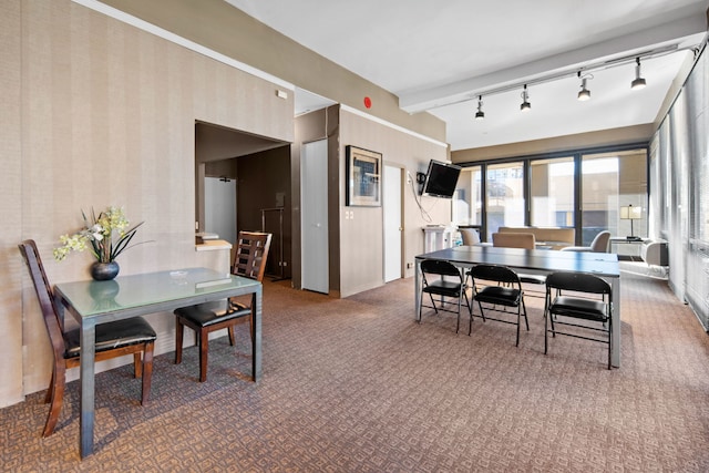 dining space with beam ceiling, carpet, and track lighting