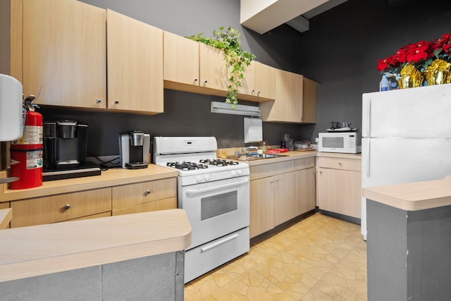 kitchen with light brown cabinetry, sink, white appliances, and light tile floors