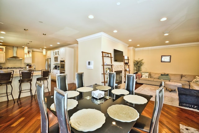 dining space with a stone fireplace, dark hardwood / wood-style flooring, ornamental molding, and sink