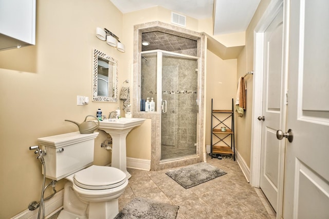 bathroom featuring tile patterned flooring, a shower with shower door, and toilet