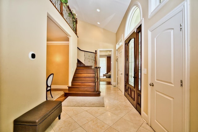 entrance foyer with crown molding and high vaulted ceiling